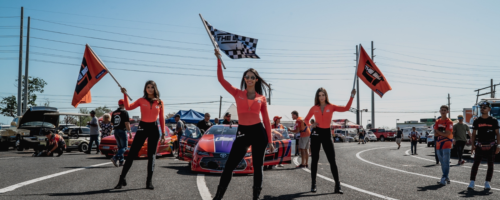 tres mujeres sosteniendo banderas en la pista de carreras