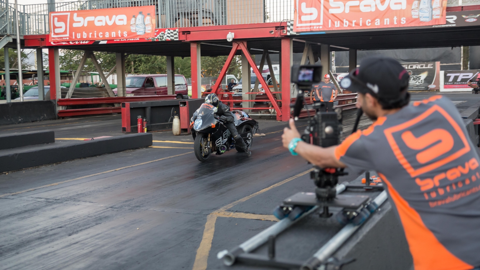 man filming motorcycle on racetrack using brava motorcycle oils
