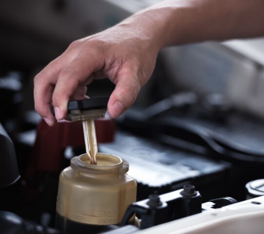man putting power steering fluid in an engine
